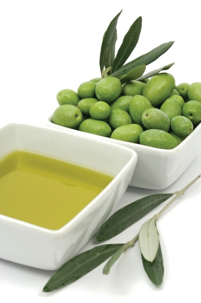 Whole green olives beside small white dishes of olive oil