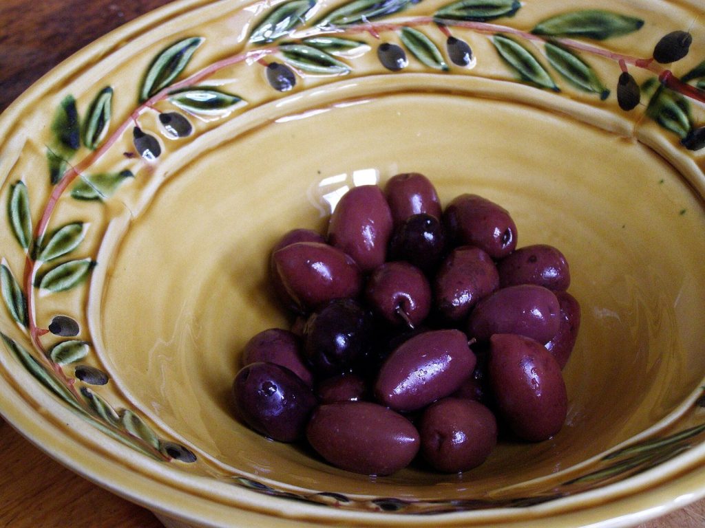 A ceramic bowl of small dark purple table olives