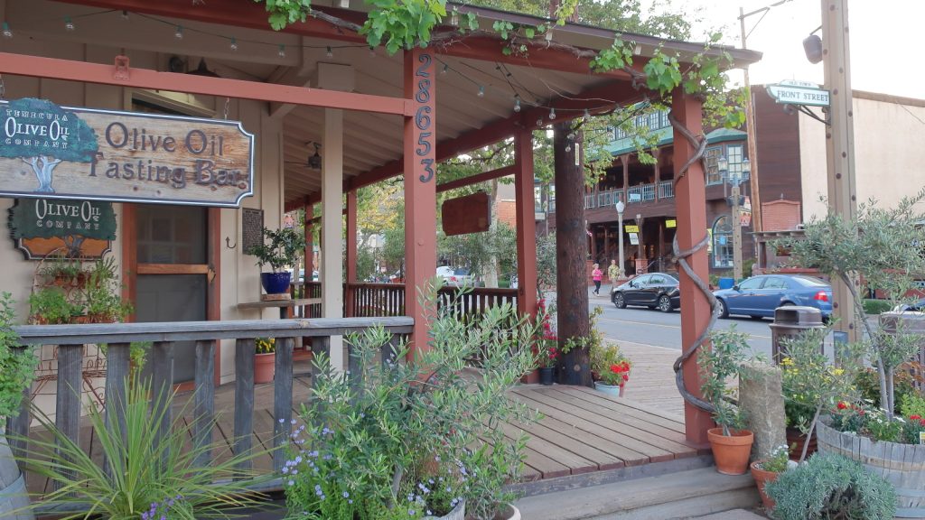 The wooden porch of the Temecula Olive Oil Company in California, with a hanging sign reading Olive Oil Tasting Bar.