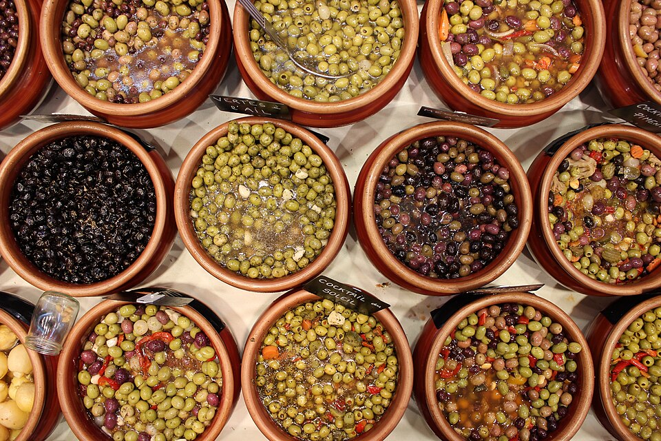 Wooden bowls of marinated green, black and mixed olives at a French market stall