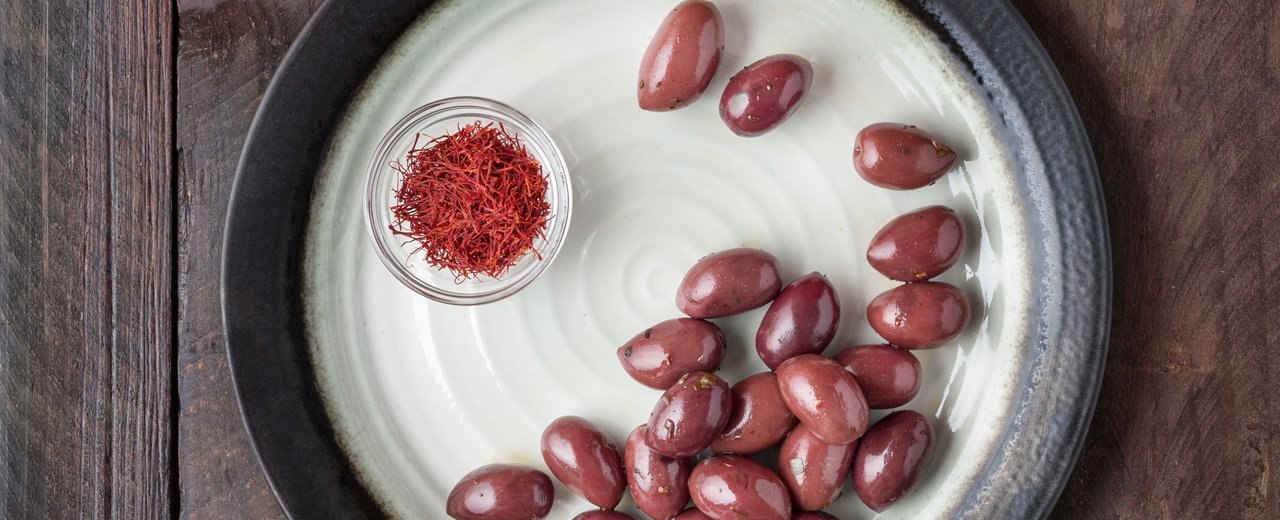 Purple Kalamata olives with oil and spices, seen from above